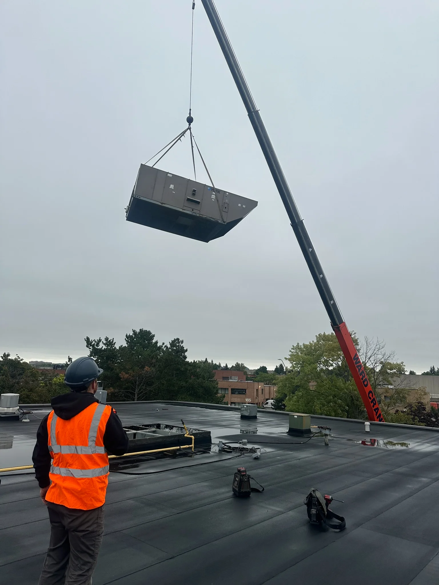 Crane lifting a rooftop unit while a White Pine technician guides the set