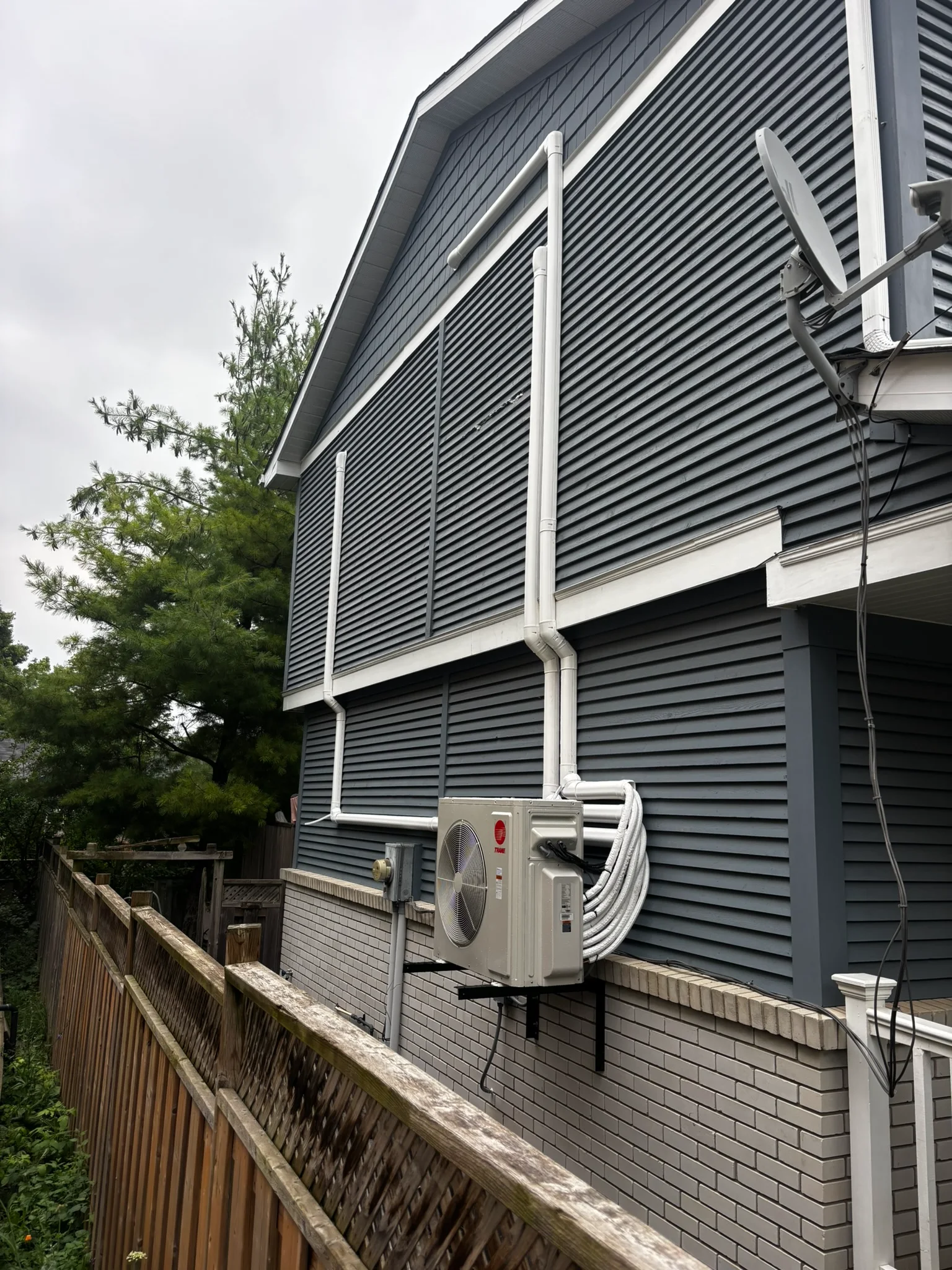 Trane ductless heat pump with clean white line-set covers on a two-storey home