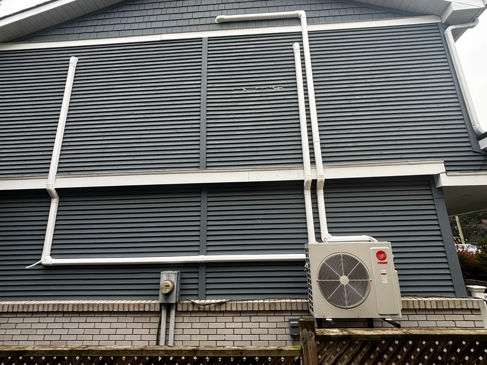 Trane outdoor heat pump with line sets routed neatly up the siding of a home